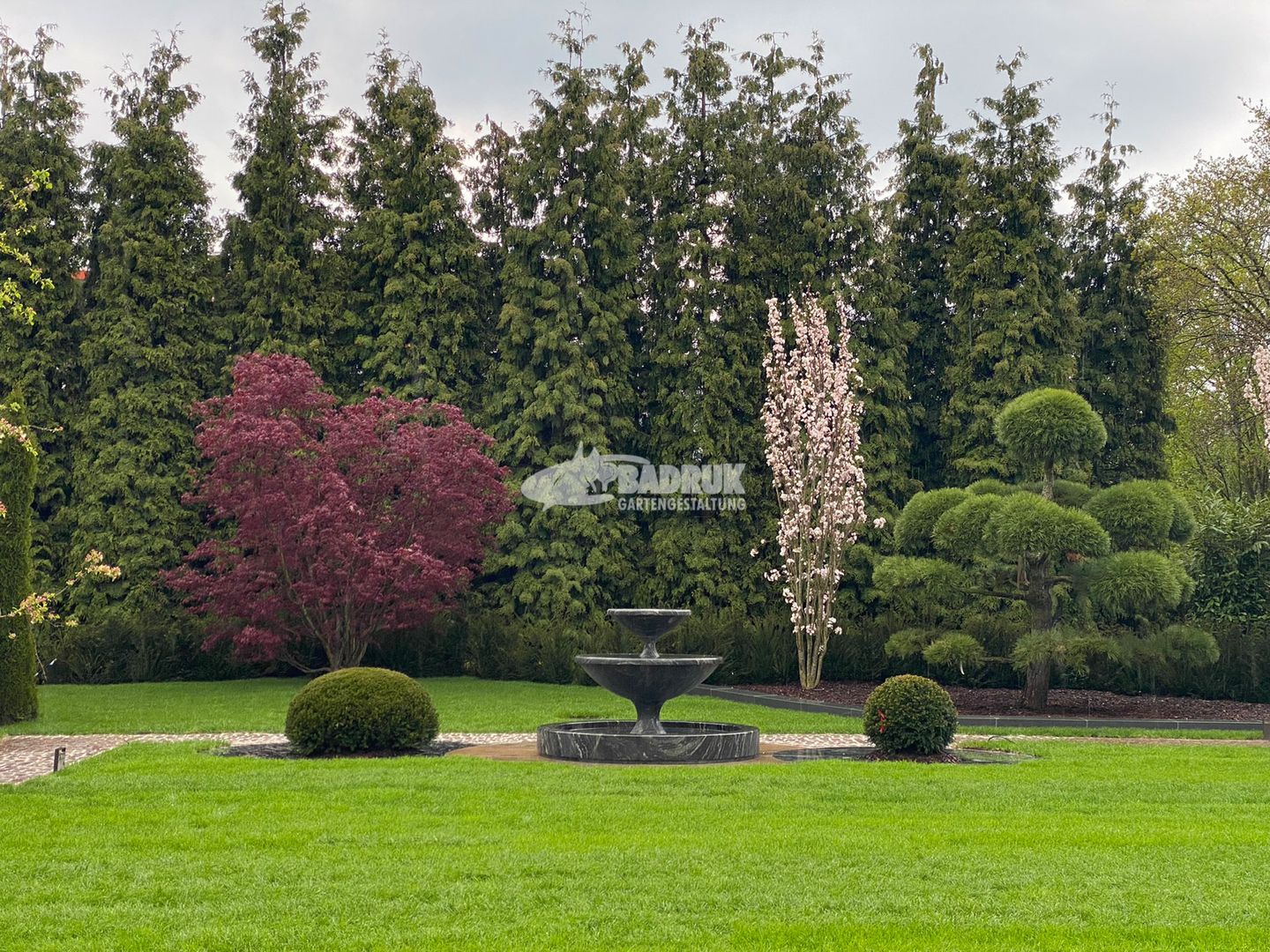 Ruhiger Garten mit einem Brunnen und Bäumen.