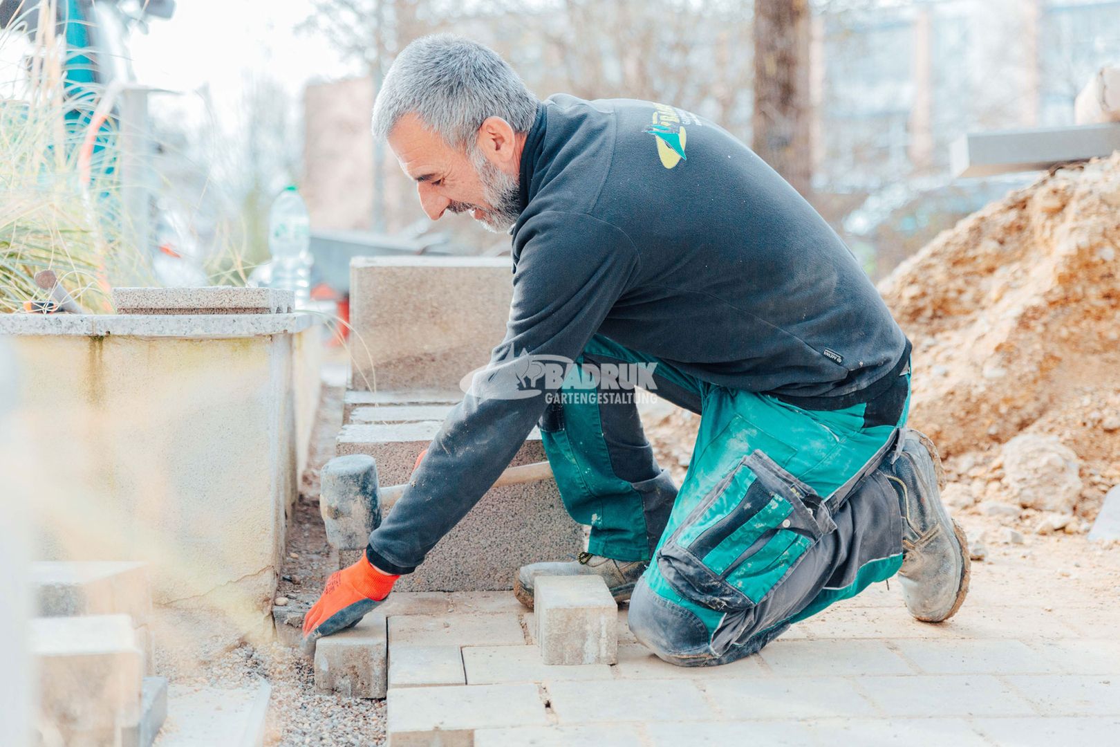 Ein Handwerker mit einem Ziegel in der Hand, der an einer Ziegelwand arbeitet und Pflasterarbeiten erledigt.