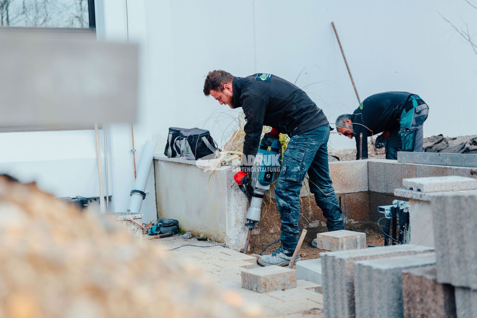 Bauarbeiter führen Pflasterarbeiten auf einer Baustelle durch, um den Boden für zukünftige Strukturen vorzubereiten.