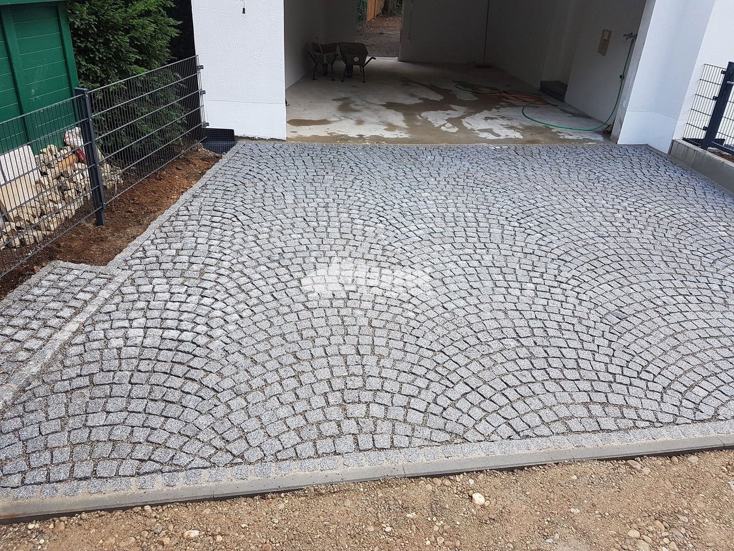 Auffahrt mit einem Steinweg und einem Ziegelpfad, die harmonisch miteinander verbunden sind.